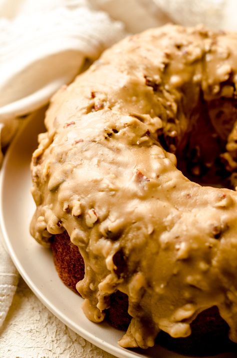 An incredibly moist and flavorful banana bundt cake flavored with rum and topped with a pecan praline icing. Chocolate Fudge Frosting Recipe, Banana Foster Cake Recipe, Praline Icing, Fudge Frosting Recipe, Bananas Foster Cake, Pecan Praline Cake, Boozy Baking, Banana Bundt Cake, Banana Bundt