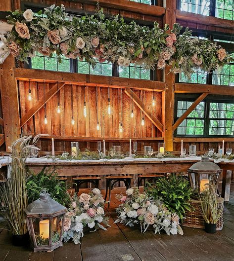 Even a rustic wedding can be romantically elegant and classy. Using forever blooms and greens with flicker candles, lanterns giving off a beautiful, personalized vibe. Rustic Wedding Decor Head Table, Head Table Wedding Rustic, Rustic Head Table Wedding, Barn Wedding Table Setting, Head Table Florals, Head Table Decorations, Rustic Barn Wedding Decorations, Head Table Wedding Decorations, Romantic Barn Wedding