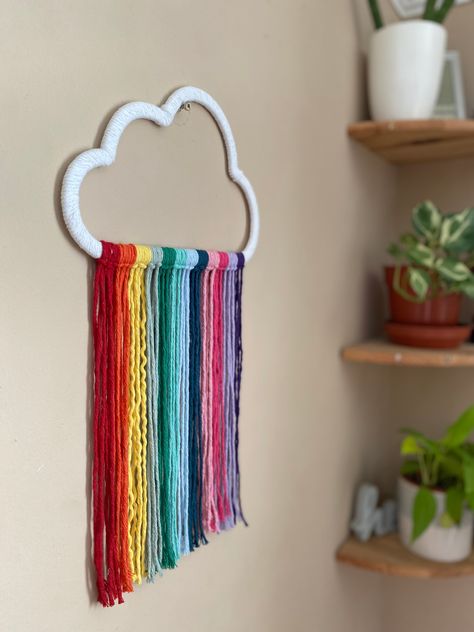 Rainbow cloud wall hanging Eco friendly materials Do you want to bring some fun, boho flair to your nursery? Look no further than this vibrant macrame rainbow cloud wall hanging! Handmade with recycled cotton in a stunning rainbow colour palette, it's the perfect way to add a splash of colour to your little one's space. This rainbow cloud hanging, nursery wall decor, is made using a wooden cloud cutout (from another small business), wrapped in white recycled cotton cord, with rainbow hanging cor Nursery Class Decoration, Classroom Ceiling Decorations, Rainbow Colour Palette, Rainbow Decor Bedroom, Cloud Hanging, Rainbow Room Decor, Cloud Decor, Simple Wall Paintings, Rainbow Hanging