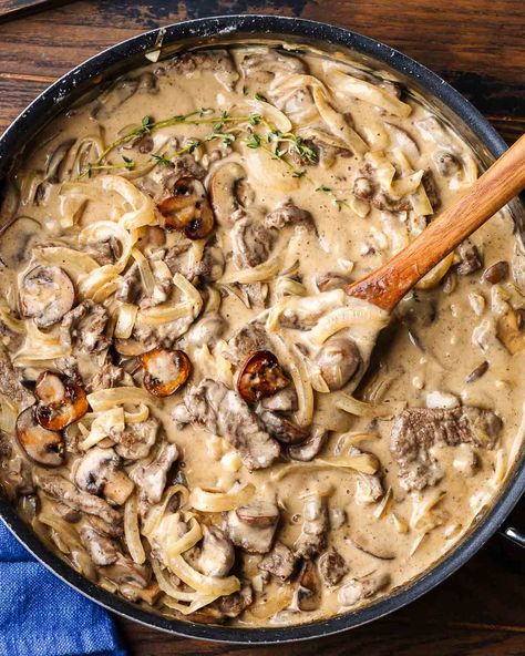 Classic Beef Stroganoff is a hearty and comforting dish that combines marinated seared steak and mushrooms in a tangy cream sauce. Beef Stroganoff is easy to make and is just perfect served over buttered noodles! #beefstroganoff #steakstroganoff #stroganoffrecipe Beef Stroganoff With Hamburger, Steak Stroganoff, Traditional Beef Stroganoff, Best Beef Stroganoff, Sip And Feast, Beef Stroganoff Easy, Steak And Mushrooms, Onion Sauce, Buttered Noodles