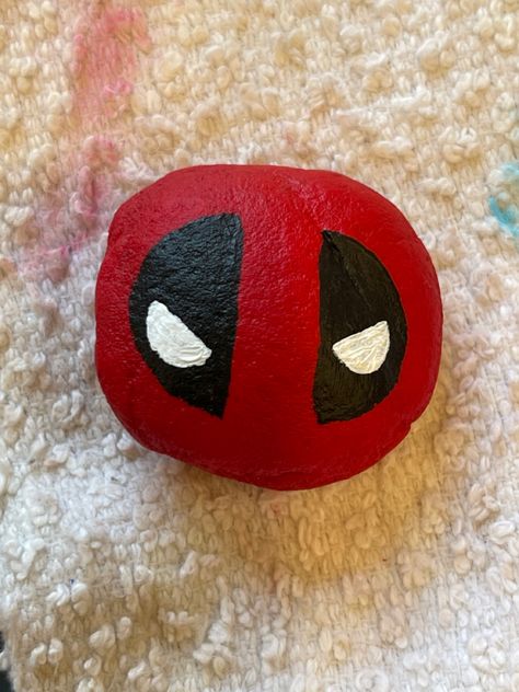 Easy Deadpool Rock Painting Idea DIY Deadpool Rock Painting, Horror Movie Rock Painting, Kirby Rock Painting, Rock Ideas Painting, Deadpool Pumpkin Painting, Marvel Painted Rocks, Square Rock Painting Ideas, Rock Painting Aesthetic, Cute Rock Painting Ideas Easy