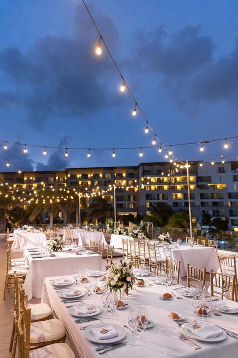 An evening wedding reception lit by market lighting. The tables are classic white with gold chairs. Dreams Natura Cancun Wedding Reception, Cancun Beach Wedding, Dreams Natura Cancun Wedding, Nighttime Outdoor Wedding, Dreams Natura Cancun, Cancun Wedding Reception, Cancun Destination Wedding, Mexico Wedding Venue, Beach Wedding Tables