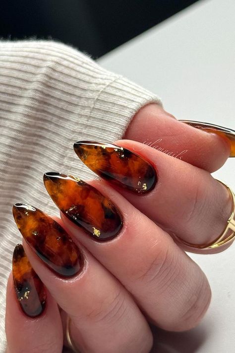 These almond-shaped nails feature a stunning tortoise shell design. Rich amber and brown tones blend seamlessly, creating a warm, organic pattern. Subtle gold flakes are carefully placed throughout, adding a touch of luxury to the sophisticated look. Each nail is beautifully glossy, amplifying the intricate details of the design. Perfect for a chic and polished style!  // Photo Credit: Instagram @iglamnails Tortishell Nails Design, Tortoise Shell Nails, Shell Nails, Sophisticated Manicure, Trendy Nail Designs, Retro Nails, Pink Ombre Nails, Fall Nail Trends, Fall Nail Art Designs