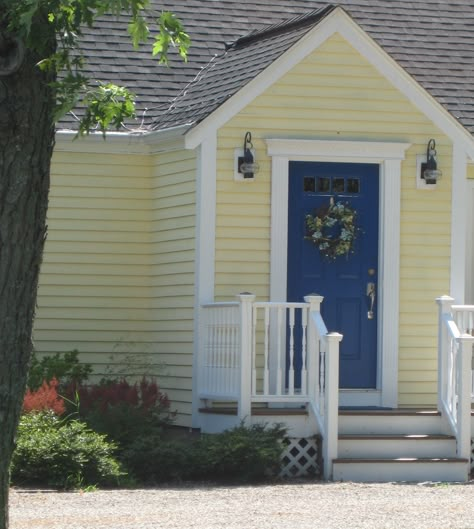 Red, yellow, and blue are primary colors that attract attention. Used alone or in combination, they will definitely grab your eye. So it's no great surprise that this house with its pale yellow sid... Yellow Siding Color Schemes Exterior, Yellow House Exterior, Exterior Gray Paint, Mailbox Makeover, Yellow Front Doors, Blue Front Door, Black Shutters, Door Paint, Door Paint Colors