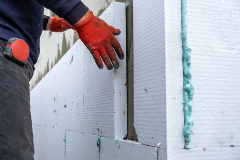 Construction worker installing styrofoam insulation sheets on house facade wall for thermal protection. Styrofoam Insulation, External Wall Insulation, Installing Insulation, Insulation Sheets, Facade Panel, Insulation Board, House Facade, Construction Worker, Tile Installation