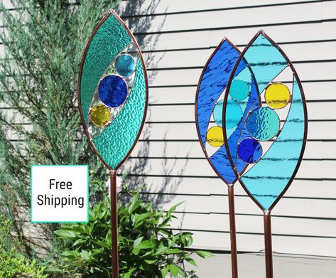 "Ellipse shaped stained glass garden art stakes. Original design. Made of transparent stained glass, ocean colors of blue, sea green, aqua and yellow . The glass portion measures 16\" height and 7.5\" width. A 40\" copper stake is included, making the total height nearly 56\". The long length of the stake will allow you to install the piece at different heights to create a visually pleasing display. The design of these abstract stakes allows the wind to flow through the open areas. Create some g Stained Glass Ocean, Stained Glass Garden Art, Stained Glass Garden, Ellipse Shape, Stained Glass Decor, Glass Garden Art, Visually Pleasing, Ocean Colors, Green Aqua