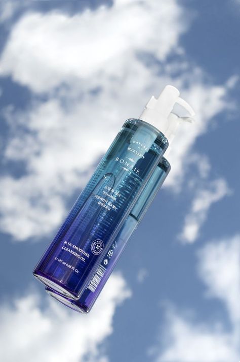 This is a product photography shot of the Bonair Oil Cleanser. It is laid on top of a surface with the sky as the background. The sky is bright blue with clouds and the oil cleanser is a beautiful blue gradient packaging. Transparent Product Photography, Blue Skincare Photography, Mirror Product Photography Ideas, Mirror Sky Photography, Blue Skincare Packaging, Product Photography With Mirror, Reflection Product Photography, Sky Product Photography, Clean Product Photography