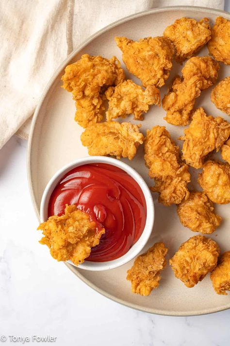 Chicken nuggets in ketchup on a plate.