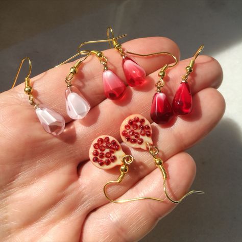 Set of unique, elegant pomegranate seed earrings. Fruit seed in ruby red, pink rose and crystal white colors or half fruit charm with tiny seeds inside. Finished with gold. Minimalist, memorable dangle earrings #pomegranateearrings #pomegranateseed #seedearrings #pomegranatejewelry #pomegranatelover #minimalistearrings #redseed #redpomegranate #whitegoldearrings #cutetinyearrings Pomegranate Seed Jewelry, Pomegranate Accessories, Persephone Design, Fruit Earring, Fruit Accessories, Interesting Earrings, Cottagecore Earrings, Pomegranate Jewelry, Earrings Charms