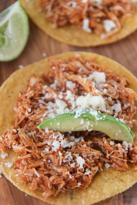 a close up of a tortilla on a wooden cutting board topped with an avocado slice and cojita cheese. Instant Pot Chicken Tinga, Chicken Tinga Tostadas, Tinga Tostadas, Chicken Tinga Recipe, Chicken Tinga, Chicken Tostadas, Cotija Cheese, Best Instant Pot Recipe, Insta Pot