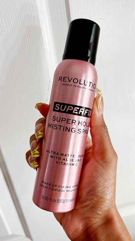 Black woman holding Makeup Revolution Superfix Makeup Fixing Spray Finishing Spray Makeup, Fixing Spray Makeup, Revolution Makeup, Best Matte Setting Spray, Makeup Revolution Setting Spray, Makeup Fixer Spray, Affordable Setting Sprays, Waterproof Setting Spray, Best Makeup Setting Spray