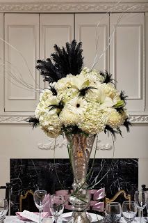 Black, white, and silver floral arrangement with feathers Gatsby Floral Centerpieces, 1920 Flower Arrangements, Great Gatsby Flower Arrangements, Gatsby Flower Arrangements, Masquerade Ball Flower Arrangements, 1920s Flower Arrangements, Art Deco Flower Arrangements, Masquerade Flowers, 1920s Flowers