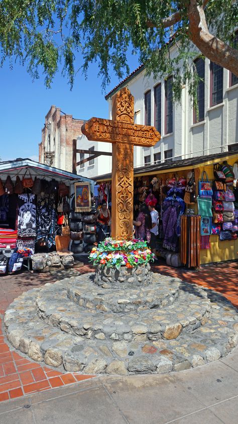 The wooden cross at the entrance of Olvera Street on January 25, 1964. Behind the cross is the El Sombrero puesto, or vending stand, with a piñata and other wares for sale. Olvera Street, Golden Coast, Santa Monica Beach, Street Vendor, Mexican Street, Mexican American, Coastal Cities, City Of Angels, January 25