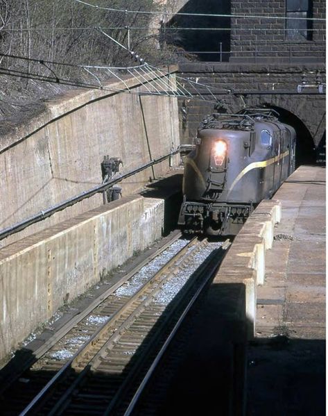 1961 sees a GG1 exiting the North River Tunnel, North Tube. The portal house above the portal and the third rail give it away, along with the high concrete walls. Penn Station Nyc, Lionel Trains Layout, Union Pacific Train, Ho Scale Train Layout, Third Rail, Railroad Art, Penn Station, Commuter Train, Concrete Walls