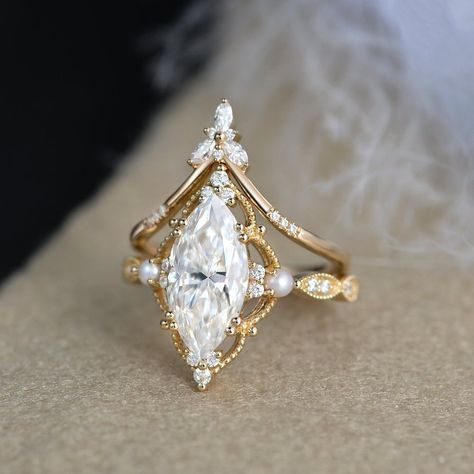 2ct Marquise Moissanite Pearl Engagement Ring Set Yellow Gold Moissanite Chevron Band Vintage Bridal Set 2pcs Flower Halo Ring art deco Milgrain * Ring Material: solid 14k white gold, rose gold, or yellow gold  * Center Stone: Colorless Moissanite   5x10mm, about 1ct   6x12mm , about 2ct    7x14mm, about 3ct * Side Stone: Colorless Moissanite, Natural Pearls, about 0.28ct * Bandwidth: 1.6mm 2-3 WEEKS PROCESSING TIME MADE IN US * Shipping * FREE SHIPPING WITHIN THE USA! * Certificate * All the it Pearl Engagement Ring Set, Marquise Moissanite Engagement Ring, Pretty Engagement Rings, Dream Wedding Ring, Milgrain Ring, Moissanite Engagement Ring Set, Flower Halo, Pearl Engagement Ring, Cute Engagement Rings