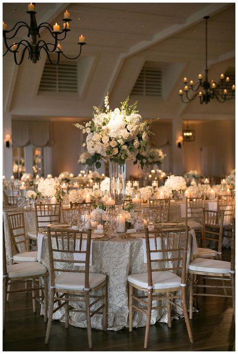 Gold, ivory and white wedding reception decor with white florals in glass vessels, place settings of gold-rimmed crystal and gold-rimmed glass chargers, floating candles, textured linens and natural wooden chairs. Event design and florals by Bella Flora, Used Wedding Decor, Wedding Reception Chairs, White Weddings Reception, White Wedding Decorations, Fun Wedding Decor, Tafel Decor, Wedding Reception Centerpieces, Reception Centerpieces, Wedding Table Decorations