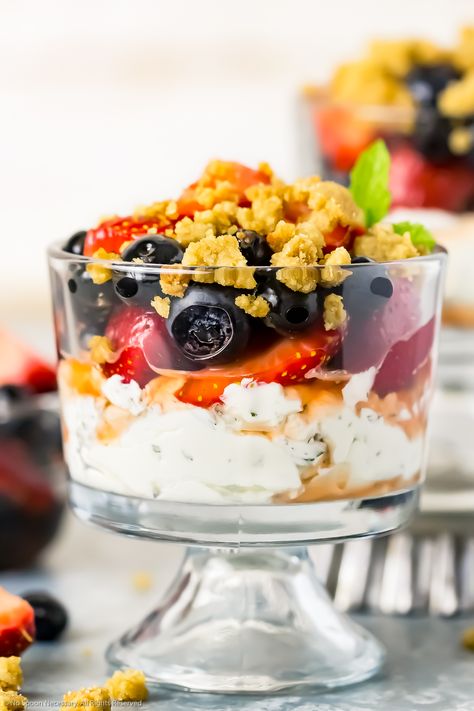 Straight on shot of a Fruit and Yogurt Parfait - which consists of layers of mint whipped yogurt, macerated fruit and graham cracker streusel - in a small parfait glass, with an additional parfait and small bowl of fruit blurred in the background. Graham Cracker Streusel, Whipped Greek Yogurt, Whipped Mascarpone, Fruit And Yogurt Parfait, Whipped Yogurt, Berry Parfait, Fruit Parfait, Fruit Crisp, Blueberry Breakfast