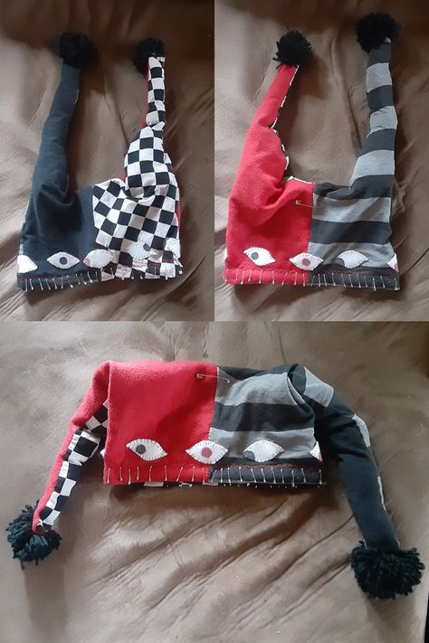 A jesters hat consisting of 4 panels: solid red, solid black, striped grey and black, and checkered white and black. It has two long 'tails' that end in yarn pom poms, a line of safety pins around the rim, and 8 simple eye patches also around the rim. Jester Hat, Funky Hats, Battle Jacket, Hat Patterns To Sew, Diy Clothes Design, Old Shirts, Felt Fabric, Fabric Paint, A Blanket