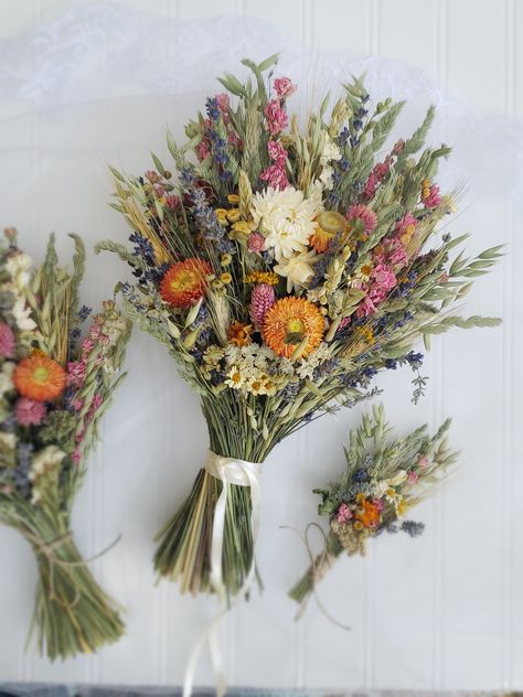 The Hippie Bouquet! One of my favorite designs! For the youthful, hippie-boho wedding! The bride's bouquet has strawflowers on both sides while the smaller bouquets are front facing. Pink and Fuschia Gomphrena, Lavender, Oats, Green Wheat, Grasses, Nigella Pods, Orange/Red and White Straw Flowers. Strawflowers are all unique.  Bouquets can come with lace wrapped stems or jute twine wrapped stems. Lace may be a little different than pictured. Boutonnieres are wrapped with hemp twine and pin on. The hairpiece is on bendable wire to hook into an up-do. Corsages tie on with hemp twine. The flower crown ties in the back with hemp twine, making it adjustable. Colorful Boho Bouquet, Spring Boho Wedding, Hippy Wedding, Unique Bouquets, Dried Flower Wedding, Wedding Flowers Wildflowers, Straw Flowers, Green Wheat, Bride's Bouquet