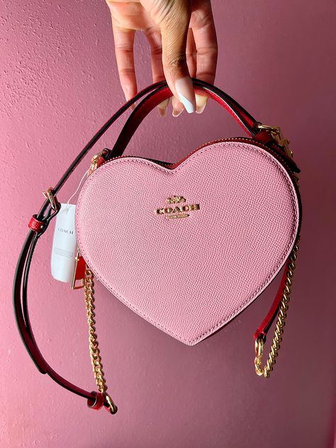 The Coach Heart Bag is the new it bag that recently dropped at the Coach Outlets. It's hard to find, but check out my blog to see how I was able to get one! Heart Coach Purse, Coach Bags Heart, Pink Coach Bag Aesthetic, Coach Valentine Bag, Coach Heart Bag Outfit, Heart Coach Bag, Coach Heart Purse, Pink Luxury Bag, Heart Bag Outfit