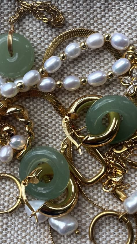 gold jewelry, pearl jewelry, & jade jewelry on a beige background Jade Aesthetic Crystal, Jade Wallpaper Aesthetic, Olive Green And Gold Aesthetic, Green White And Gold Aesthetic, Janine Aesthetic, Green And Gold Jewelry Aesthetic, Jade Jewelry Aesthetic, Jade Color Aesthetic, Green Jade Aesthetic