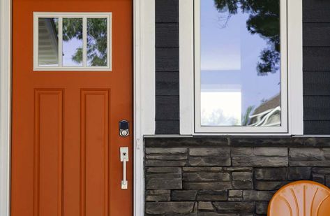 Front Door Colors for Gray Houses | Top Front Door Color Choices. orange front door. Dark gray house siding, white trim. Silver hardware. Dark gray real stone veneer. Grey House White Trim, House Doors Colors, Dark Grey Houses, Dark Blue Houses, Orange Front Doors, Best Front Door Colors, Front Door Color, Exterior Door Colors, Blue Siding