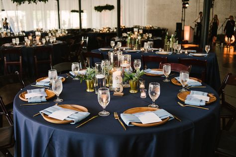 Navy Blue Wedding Reception Round Table Decor with Blue Satin Linen, Wooden Chargers with Dusty Blue Linen, Lasercut Table Number, Floating Candles in Glass Vases, Green Plant in Gold Vase | Lakeland Venue Haus 820 | Tampa Bay Rentals Over the Top Linens Wedding Reception Table Linens, Succulent Wedding Centerpieces, Blue Wedding Receptions, Round Table Decor, Blue Tablecloth, Wedding Table Linens, Wedding Reception Centerpieces, Reception Centerpieces, Hanging Candles