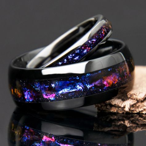 "This \"Galaxy\" his and hers black ceramic wedding ring set features matching rings with a mesmerizing design reminiscent of swirling gas and dust clouds found in galaxies, this ring boasts a stunning array of colors that evoke the celestial splendor of the night sky. Deep blues, purples, pinks, and oranges come together in a breathtakingly beautiful pattern, creating a sense of cosmic movement and dynamism that is sure to captivate the imagination.  Beautiful color shifting effect! || Features || - Couples wedding band set - Strong scratch resistant black ceramic - Domed finish - Highly scratch resistant - Beautiful color shifting galaxy style inlay - Water resistant - Comfort fit interior - Can be customized with different metals and materials - Handmade - Ideal for promise rings, weddi Galaxy Wedding, Blue Wedding Rings, Couples Rings, Space Rings, Couples Wedding Bands, Galaxy Ring, Black Galaxy, Rings Black, Magical Jewelry