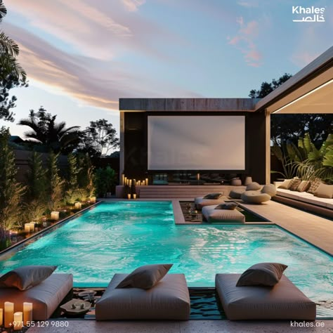 Khales designed this intricate detailed design for a modern and contemporary home.  An outdoor cinema in the garden of an ultra-modern house with a pool, couches and candle lights around it, movie screen on the wall.  For Project Management, Engineering Consultancy or Interior Design requirements, contact Khales at: Pool With Projector Screen, Outdoor Cinema Garden, Villa Pool Design, Modern House Backyard, Poolside Bar Ideas, Pool Cinema, Billionaire Mansions, House With A Pool, Landscape Residential