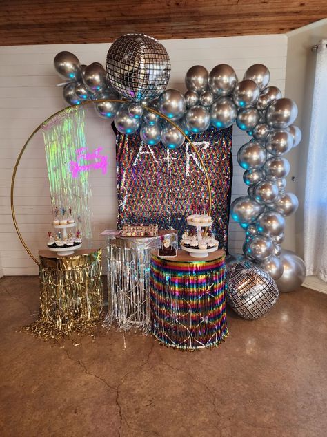 Dessert stands with chrome silver balloons and multi colored backdrop. 6ft gold round stand. Cupcakes and cake display. Through the decades themed party for adults. Disco, 70's and 80's. Disco Cake Table, Party For Adults, Disco Cake, Studio 54 Party, 70’s Disco, Dessert Stands, Silver Balloons, Through The Decades, Prom 2024