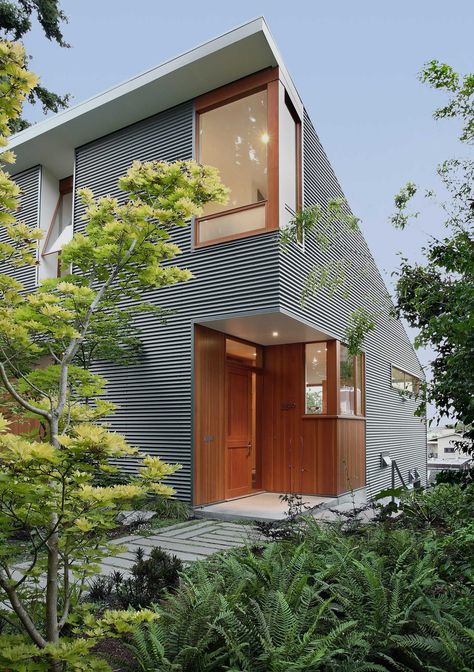 A modern house with corrugated metal siding and a wood front door and window frames. Home Siding Ideas Exterior, Shed Architecture, Corrugated Metal Siding, Funny Real Estate Quotes, Wood Window Frame, Funny Real Estate, Modern Contemporary Homes, Metal Cladding, Seattle Homes