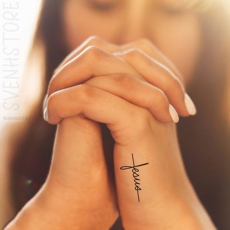 Simple Women Tattoos Ideas, Faith Tattoo On Hand, Cross With Palm Leaves Tattoo, Faith Over Fear Tatoos, Love God Tattoo, Woman’s Tatoos, He Has Risen Tattoo, Small Nursing Tattoos Simple, Dainty Scripture Tattoos