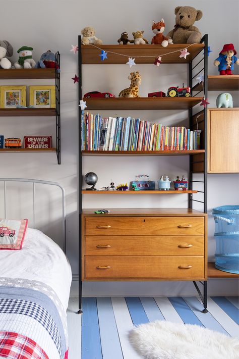 Mid century style boys room in our Edwardian period home. We painted the floorboards in different tones of blue - Lulworth Blue, Cooks Blue and Borrowed Light by Farrow and Ball. The teak of the ladderax string shelving contrasts beautifully with the cool blues and the sheepskin rug adds cosiness. See more images on our website! Mid Century Boys Room, Mid Century Kids Room, Lulworth Blue, Painted Floorboards, String Shelving, Colourful Accessories, Borrowed Light, Period Home, Kids Room Furniture