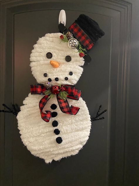 This sweet snowman wreath is handcrafted with chunky yarn on a snowman wreath frame. He has button eyes and mouth with a carrot nose and pom pom buttons for his tummy. He has a black top hat with a buffalo plaid brim and scarf. He will cheer up your door during cold winter days. Snowman Door Wreath, Snowman Wreath Diy Dollar Stores, Snowman Wreath Diy, Dollar Tree Snowman Wreath, Yarn Wreath Diy, Wire Snowman, Snowman Hat Pattern, Snowman Wreaths, Christmas Yarn Wreaths