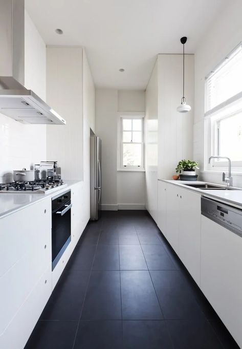 This kitchen features black tiles flooring surrounded by white walls, white cabinetry and white counters with white countertops. White Galley Kitchens, Galley Kitchen Remodel Ideas, Galley Kitchen Layout, Galley Kitchen Design, Galley Kitchen Remodel, Galley Style Kitchen, Galley Kitchens, Kabinet Dapur, Beautiful Kitchen Designs