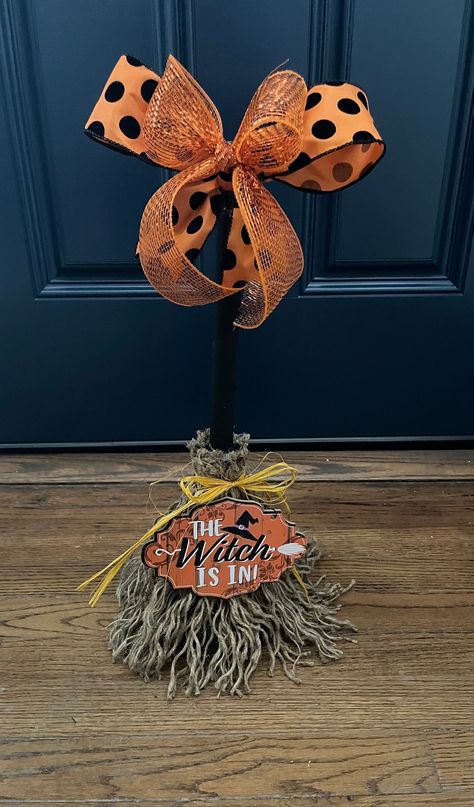 This adorable Witch Broom is all treats and no tricks! A duo of bows sit  atop of a black hand painted broom handle. Jute rope is used as bristles, it is unraveled by hand and attached to the handle. A yellow raffia bow ties up the broom while a sign announcing The Witch Is In sits bottom center of this cute broom! Unique and cute this broom will have you swept away in no time!! Made to order  For decorative purposes only Witch’s Broom, Fall Broom, Witch Brooms, Halloween Brooms, Witch Bells, Witches Broom, Dollar Store Halloween, Creepy Halloween Decorations, Halloween Traditions