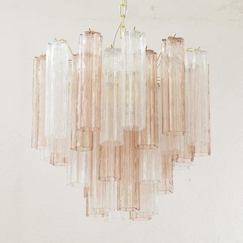 A great classic of italian vintage design and at the same time a magnificent contemporary chandelier in mid-century murano glass. the "tronchi" suspension lamp is made up of elements in blown glass tubes called "tronchi" due to their shape which resembles bark. the glass trunks are pink and crystal in color and are mounted on a metal structure with a brass finish. the chandelier has two levels and is made up of 36 hanging glass elements. each piece is hand blown in italy and measures approximately 30cm in length.  this stunning venetian style chandelier is a great designer piece that is sure to add luxury and class to your space.    type: made in italy chandelier collection: logs dimensions: ø58 x h52 cm + chain approximately 50 cm (20") and rosette (26" l x 26" h) shape: round pendant on Vibey House, Quartz Chandelier, Alice Lane, Pink Chandelier, Iron Stone, Blown Glass Chandelier, House Lighting, Unique Chandeliers, Art Deco Chandelier