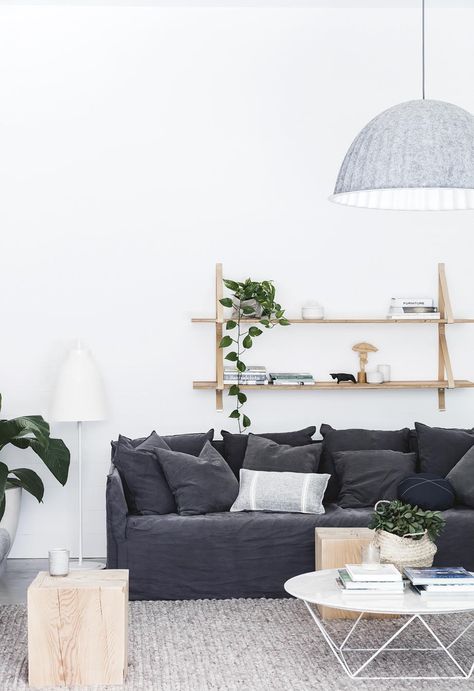 A pale grey Muuto pendant light hangs over a textured neutral rug in the living room. A charcoal couch adds contrast to the white walls and hanging shelves. | A creative couple combined their skills to build a modern beach house | Inside Out - August 2018 | Styling: :Sarah Ellison | Photographer: Maree Homer Charcoal Couch, Shelves Lighting, Beach House Room, Beach Home Interiors, Beautiful Beach Houses, Beach House Interior Design, Coastal Living Rooms, Room Shelves, Modern Beach House