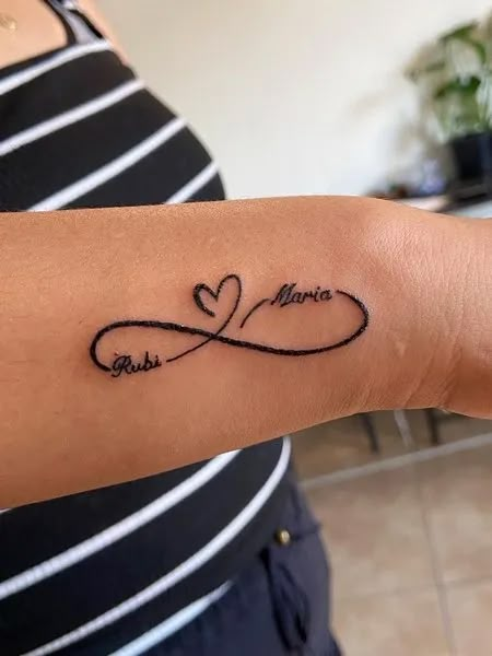 Infinity Tattoo With Names Infinity With Names Tattoo Designs, Tattoo Names Idea, H Name Tattoo Designs, Wrist Tattoos For Women With Names, Mommy Of Two Tattoos, Small And Simple Tattoos For Women, Infinity Tattoo With Year, Tattoo Name With Design, Heart And Name Tattoo Ideas