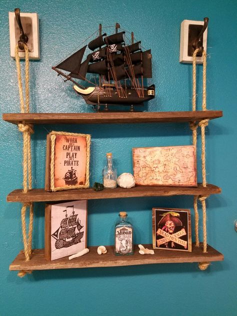 Used old fence boards and some rope I bought to create this cute shelf for pirate bathroom theme Pirates Room Decor, Ship Themed Bedroom, Pirate Core Decor, Fish Theme Room, Pirate Aesthetic Home Decor, Pirates Of The Caribbean Bathroom, Pirate Aesthetic Bedroom, Pirate Bedroom Aesthetic, Dark Nautical Bathroom