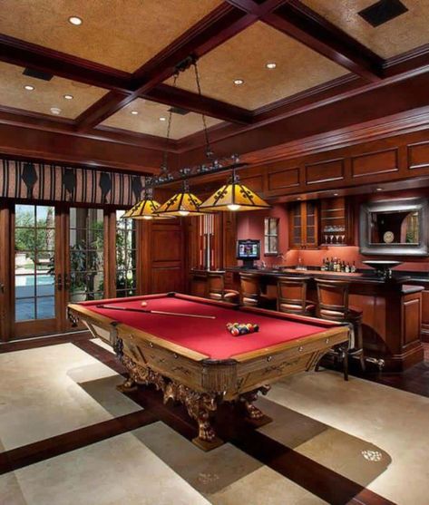 Sophisticated man cave with an ornate clawfoot pool table across the bar area sporting a unified look. It is lighted by yellow pendants that hung from the coffered ceiling. Game Garage, Pool Room Ideas, Pool Table Design, Snooker Room, Garage Game Rooms, Pool Table Room, Billiard Pool Table, Man Cave Room, Game Room Basement