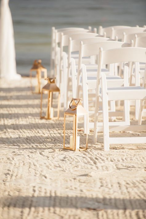 Gold Lanterns with white chairs down the ceremony aisle  Beach weddings  Ocean pointe Suites Weddings Beach Wedding Lanterns, Beach Wedding Aisles, Key Largo Florida, Lantern Decor Wedding, Beach Wedding White, Ceremony Candles, Wedding Isles, Ceremony Aisle, Dream Beach Wedding