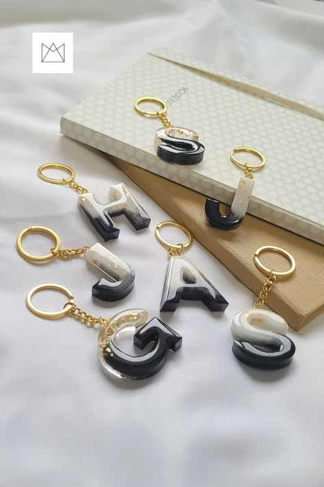 A couple of Black and White Resin Letter Keychain with Gold flakes, attached to gold metal keychain. Resin Keychain Photography Ideas, Black And White Resin Keychain, Simple Resin Crafts, Resin Photography Ideas, Keychain Photography Ideas, Black Resin Keychain, Resin Letter Keychain Ideas, Resin Photography, Giveaway Graphic