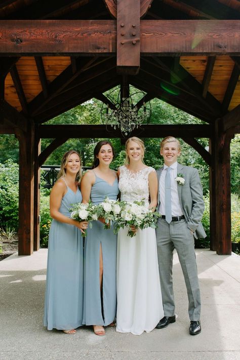 Bridesmaids are wearing pastel blue spaghetti strap dresses. Groomsman is wearing light grey formal suit. Bride is wearing Katrina Tuttle wedding dress. Photo by Sandra Monaco. #entouragecolorpalette #bridesmaiddressinspiration #pastelbridesmaiddress #mooresclothingsuit #neutralentourage #outdoorwedding #augustwedding #AncasterMillWedding Dusty Blue Wedding Family Photo, Pale Blue Bridesmaid Dresses, Ancaster Mill, Outdoor Chapel, Suit Bride, Pastel Bridesmaid Dresses, Wedding Tux, Family Wedding Photos, Light Grey Suits