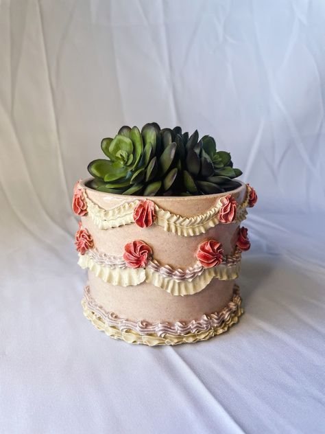 Ceramic Planter is sculpted to look like a cake featuring a light pink base with light purple, dark pink and white vintage cake piping. The piece features a whole in the bottom for water draining. Vintage Cake Piping, White Vintage Cake, Indoor Plants Succulents, Pot Cakes, Purple Ceramic, Cake Piping, Bakery Kitchen, Bakery Decor, Plants Succulents