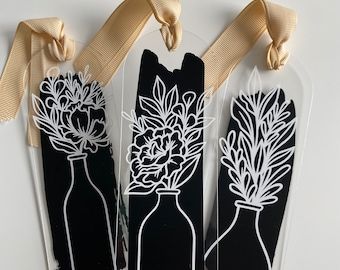 3 black and white vinyl book marks with vinyl floral designs, accent3ed with ribbon. Cricut Vinyl Bookmarks, Popular Cricut Projects, Bookmark Vinyl, Vinyl Crafts To Sell, Vinyl Bookmarks, Acrylic Bookmark Ideas, Cricut Bookmarks, Acrylic Bookmarks, Bookmarks For Books