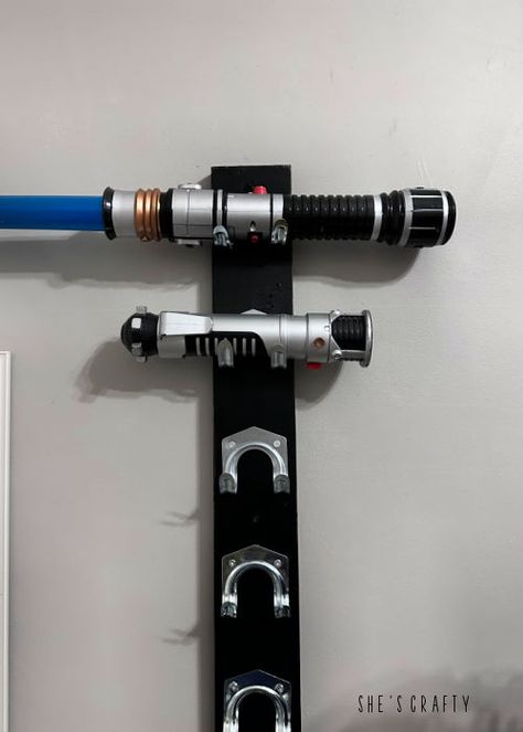 Star Wars lightsaber holder made out of wood and tool hooks. Lightsaber Holder, Star Wars Lightsaber, Happy Star Wars Day, Tool Hooks, Black Chalk Paint, Build A Wall, Star Wars Light Saber, All Of The Lights, Utility Hooks