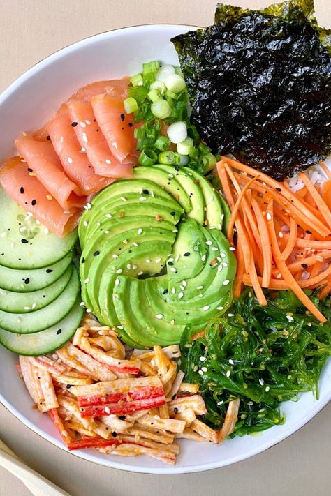 sushi bowl with smoked salmon, spicy mayo crab salad, avocado, cucumber, seaweed, carrots, green onions, and roasted seaweed over white rice and served in a white bowl with a pair of chopsticks Yummy Bowls, Cooking Sushi, Salad Bowl Recipes, Sushi Bowl Recipe, Sushi Bowls, Sushi Salad, Easy Sushi, Diy Sushi, Poke Bowls