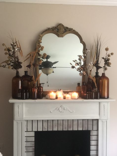 Earthy Mantle Decor, Cottagecore Mantle, Amber Bottles Decor, Amber Glass Decor, Vintage Mantle Decor, Light Academia Living Room, Fall Fireplace Mantel, Cozy Cabin Decor, Glass Bottle Decor