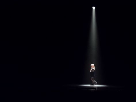 A woman is alone on stage under a spotlight. Theater Spotlight, Avatar Show, Chinese Whispers, Stage Spotlights, Film Dance, Spotlight Lighting, Dance Stage, Lighting Guide, Cinematic Photography